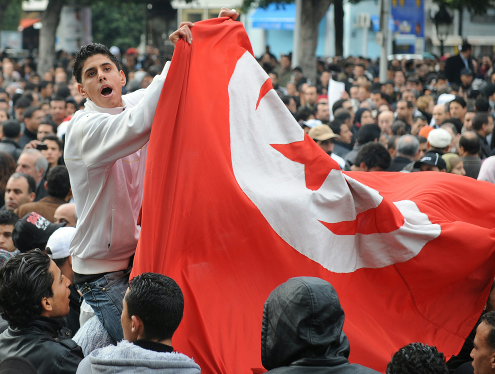 Tunisian pro-government demonstrators hold a national flag during a protest on Habib Bourguiba Avenue in Tunis January 25, 2011. (FETHI BELAID/AFP/Getty Images)